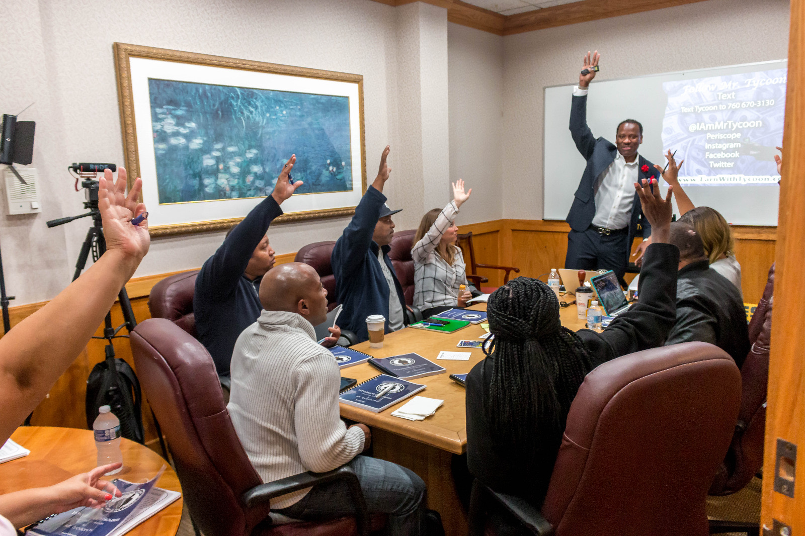 A workshop table with every hand raised as Mr. Tycoon teaches