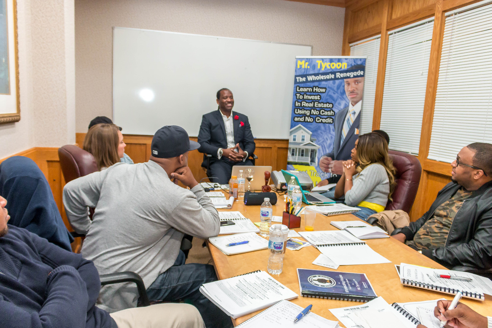 Mr. Tycoon seated at the head of a full workshop table